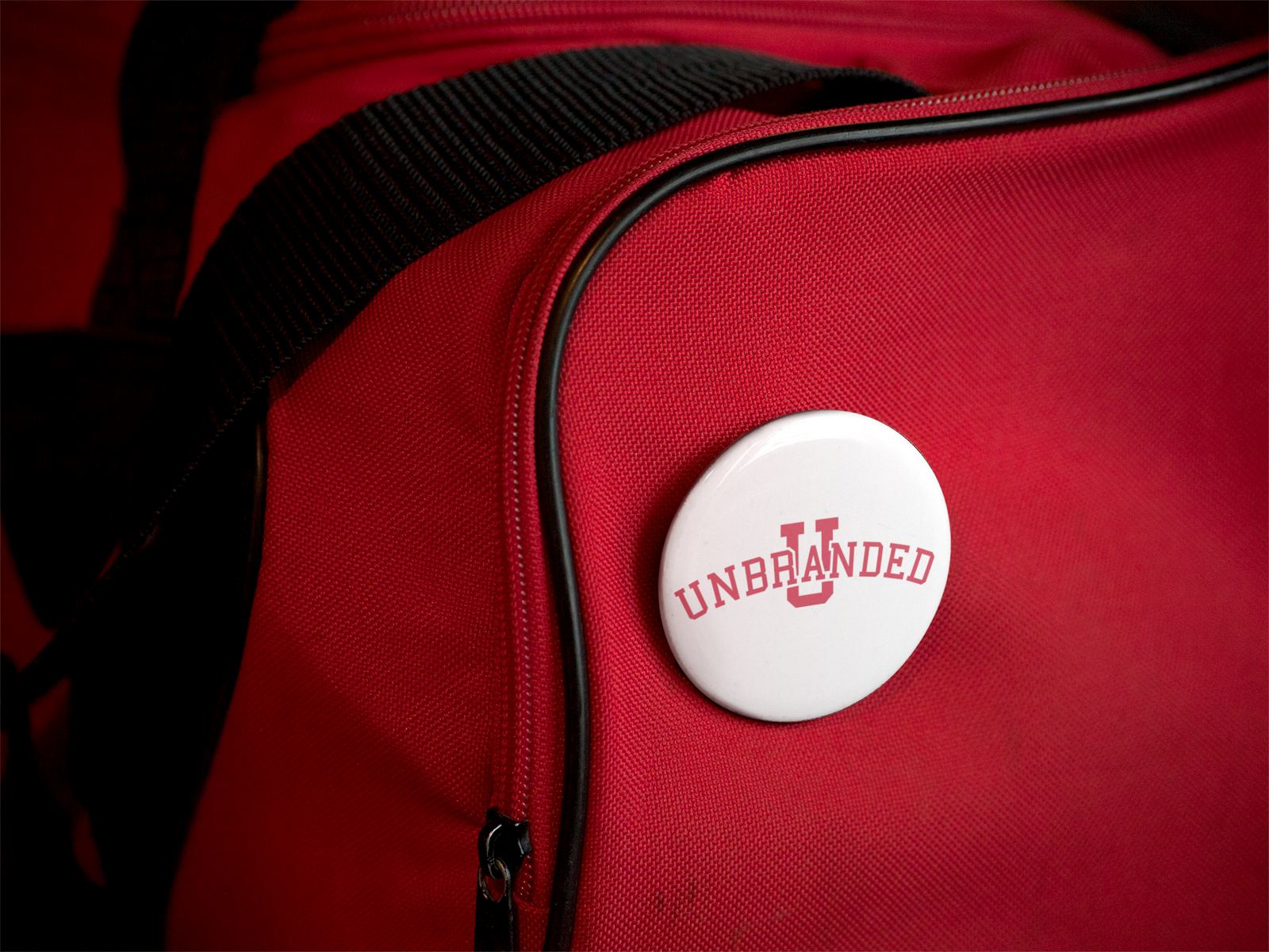 A red backpack with an Unbranded button pinned to it